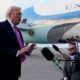 President Donald Trump speaks to reporters on an airport tarmac, with Air Force One visible in the background.