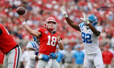 Action shot from the Georgia vs. Ole Miss game showing a Bulldogs player in a red jersey breaking a tackle from a Rebels defender, highlighting the intensity of their comeback victory.